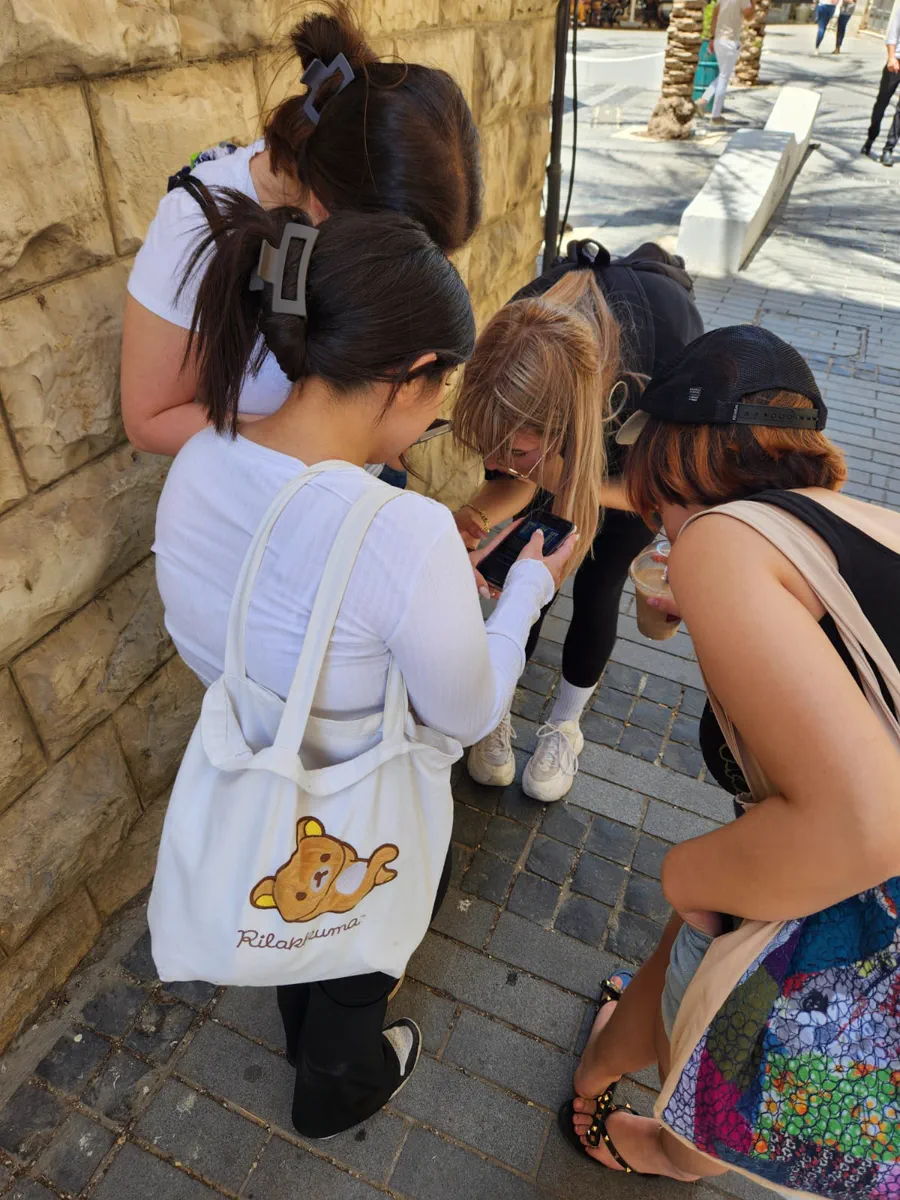 קבוצת שחקנים פותרת משימה בטלפון במהלך Quest City בחיפה